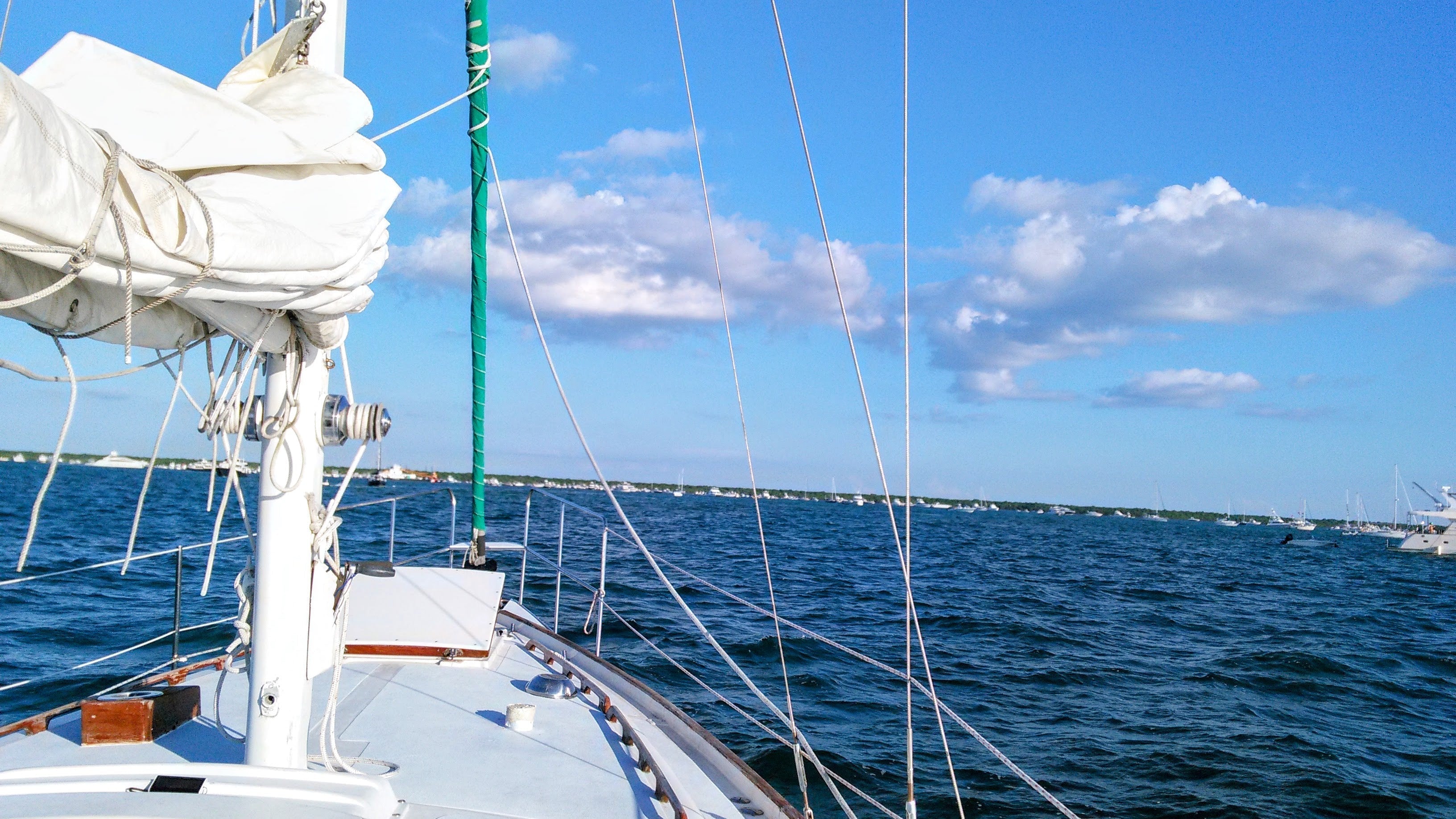 "View from the deck of Southern Star, the Sailing Religion vessel, under clear skies and calm seas—sails furled, lines tight, and freedom ahead."