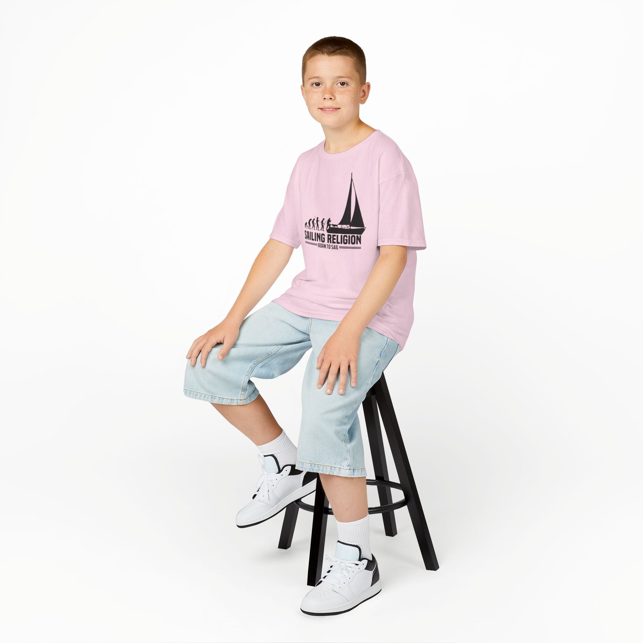 "Child wearing a pink shirt featuring the Sailing Religion logo, combining nautical-inspired style and comfort. Perfect for young sailors and beach enthusiasts."