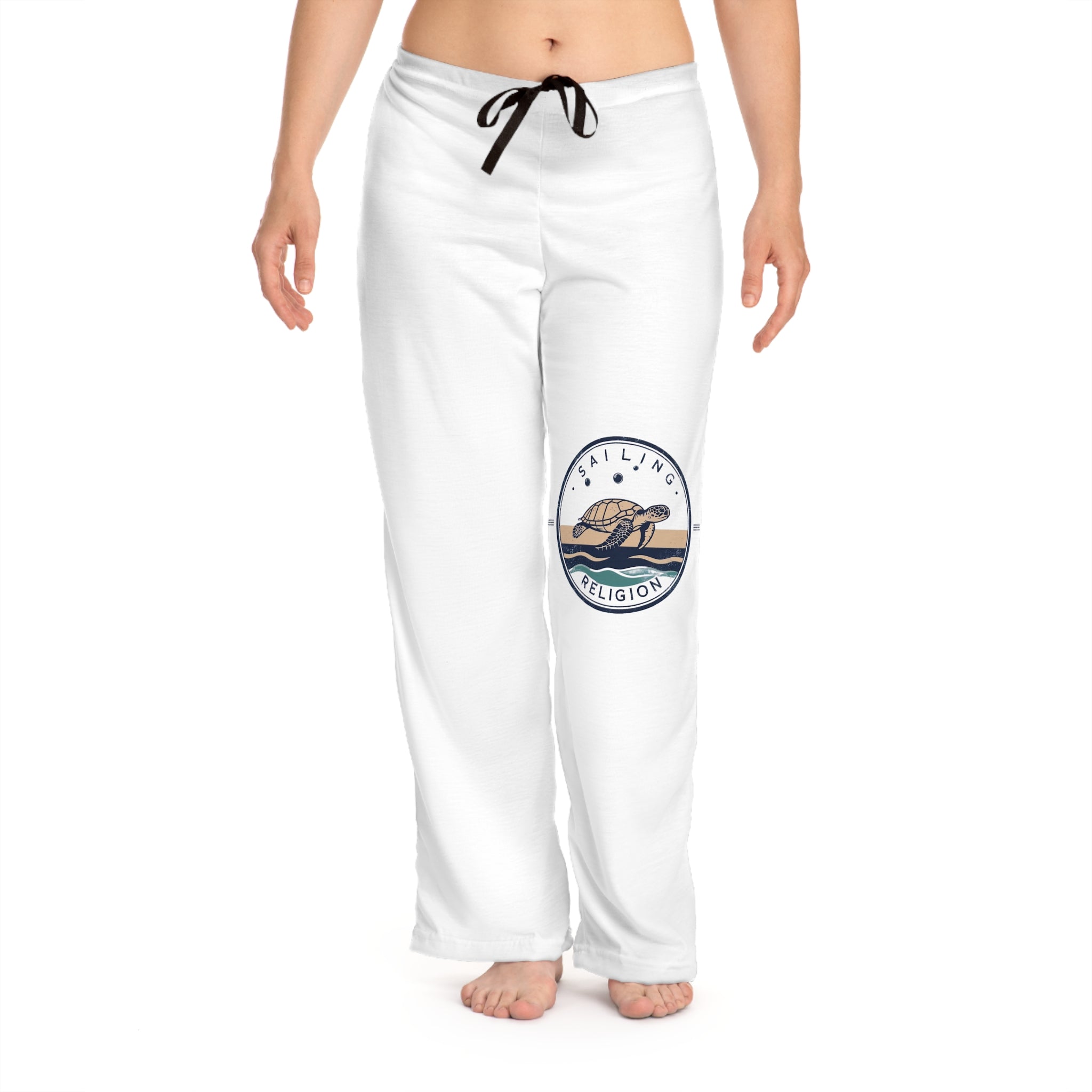 Woman wearing white Sailing Religion lounge pants featuring a sea turtle ocean graphic on the leg — soft coastal-inspired women’s pants designed for comfort, movement, and nautical lifestyle.